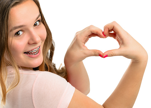 Beautiful happy teenage girl shows gesture heart on a white background.