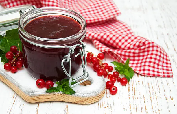 Redcurrants  jam  with fresh berries on a wooden background