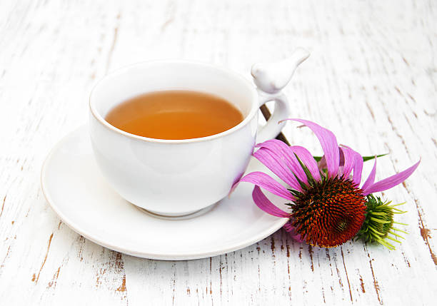 Cup of tea  with purple echinacea Cup of tea with purple echinacea on a wooden background coneflower stock pictures, royalty-free photos & images