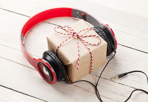 Gift box with headphones on wooden table