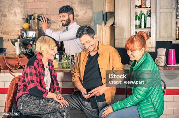 Friends Group Having Fun Using Smartphone At Hipster Cocktail Bar Stock Photo - Download Image Now