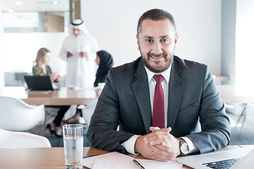 Businessman 40s at work with laptop smiling towards camera