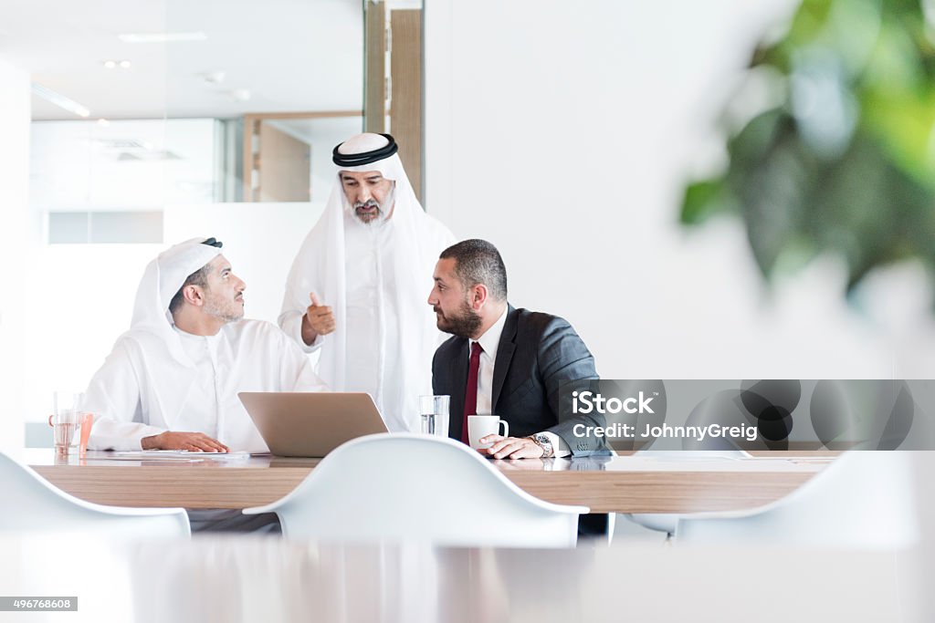 Three Arab businessmen in business meeting in modern office Business professionals using laptop, discussion, teamwork, co-operation United Arab Emirates Stock Photo