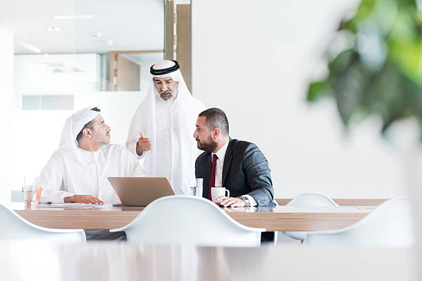 Three Arab businessmen in business meeting in modern office Business professionals using laptop, discussion, teamwork, co-operation united arab emirates photos stock pictures, royalty-free photos & images