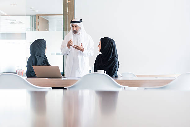 Arab businessman and women meeting in modern office, Dubai Three business people wearing traditional clothing in meeting, United Arab Emirates. arabian peninsula photos stock pictures, royalty-free photos & images