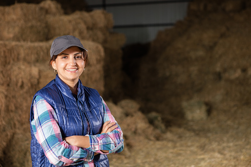 Young woman farmer in posing in hayloft.