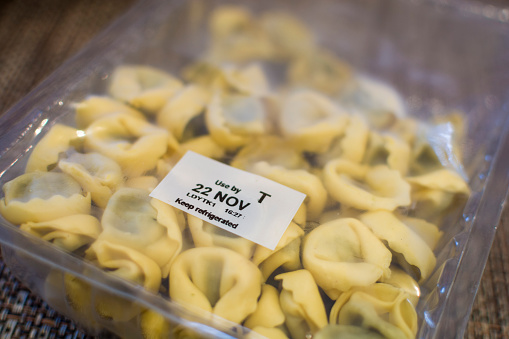 A vacuum sealed packet of pasta shells. Use By date stamp says 
