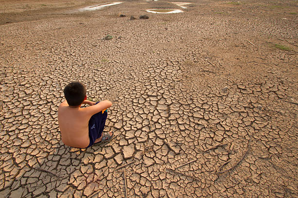 istock Children sit on cracked earth 496771358