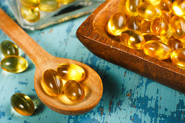 Cod Liver Oil Capsules Cod Liver Oil Capsules on wooden spoon animal internal organ stock pictures, royalty-free photos & images