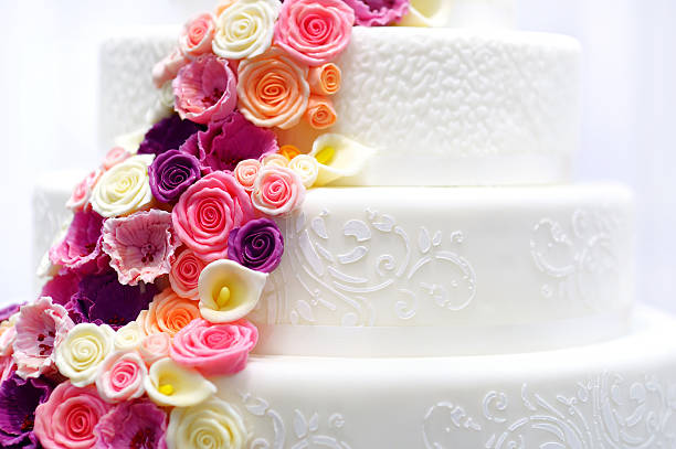 White wedding cake decorated with sugar flowers Detail of a white wedding cake decorated with pink sugar flowers wedding cake close up macro stock pictures, royalty-free photos & images