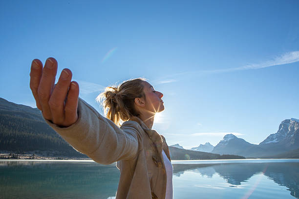 jovem mulher com os braços abertos pelo lago de ascensão do sol - bow lake imagens e fotografias de stock