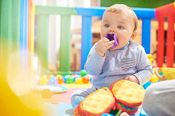 young baby boy playing with his toys in playpen - babybox stockfoto's en -beelden