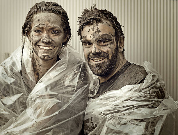 happy couple posing after crossing mud obstacle happy couple posing after crossing mud obstacle people covered in mud stock pictures, royalty-free photos & images