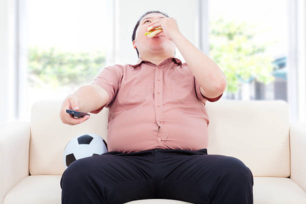 gordura negócios homem beber cerveja e sentado no sofá - remote fat overweight dieting imagens e fotografias de stock