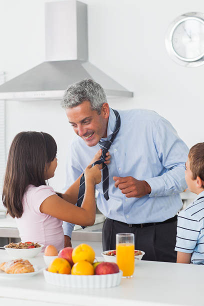 istock Daughter fixing her fathers tie with son in the kitchen 496796357