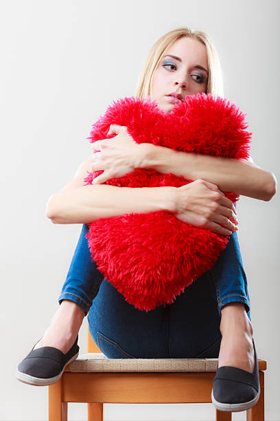 istock Sad unhappy woman holding red heart pillow 496796746