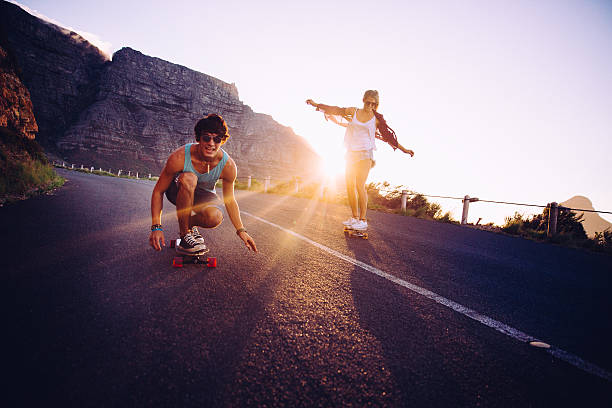 amigos tabla larga en la calle al atardecer - patinaje en tabla larga fotografías e imágenes de stock