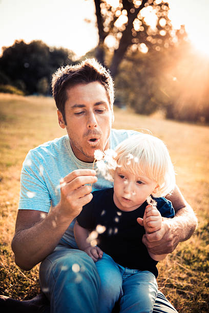istock Father and son blowing dandelions 496798301