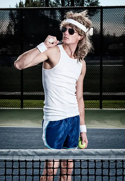 A retro 80's style guy playing tennis on a court.