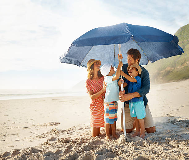 Setting up the shade Shot of a happy young family setting up a beach umbrellahttp://195.154.178.81/DATA/i_collage/pu/shoots/784348.jpg parasol photos stock pictures, royalty-free photos & images