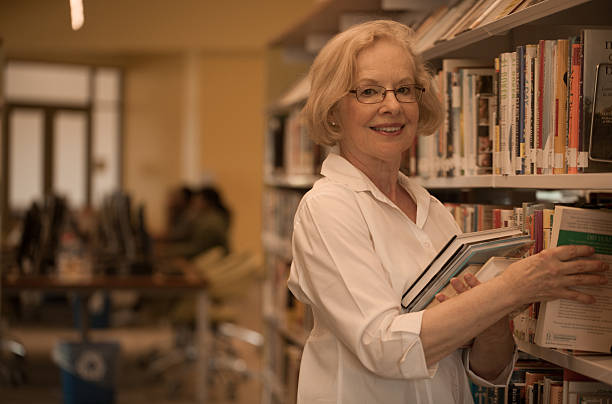 Senior woman shelfing books in library smiling
