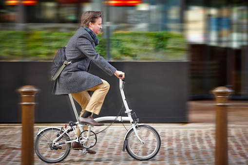 Middle aged businessman going to office by brompton cycle - Motion blurred