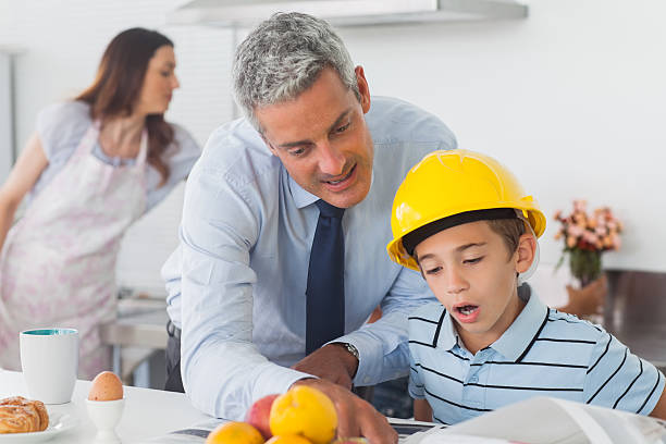 istock Father showing son his blueprints as he is wearing hardhat 496800101