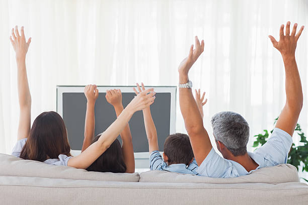 istock Family watching televison and rising theirs arms 496812681