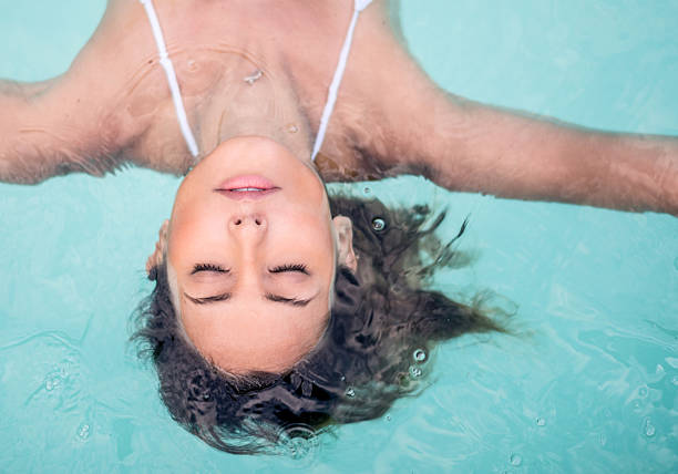 mulher relaxante na piscina - flutuando na água imagens e fotografias de stock