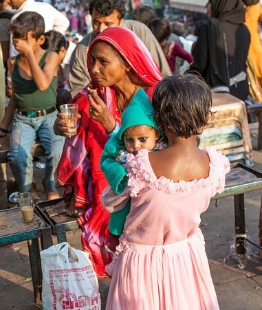 Delhi, India - November 10, 2011:  young girl holds her baby sister in the arm  at the Meena Bazaar Market in Delhi, India. Shah Jahan founded the bazaar in the 17th century inspired by the architecture of the Isfahan Bazaar.