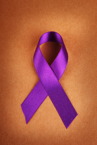 Purple awareness ribbon on brown paper background