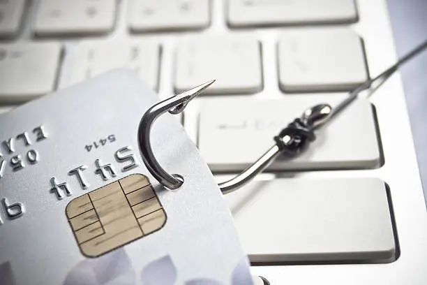 phishing - fish hook with a credit card on white computer keyboard