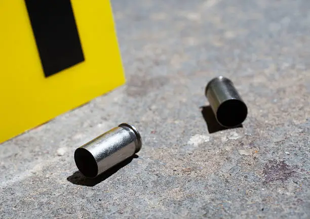 Pair of handgun casings that are on concrete with an evidence marker