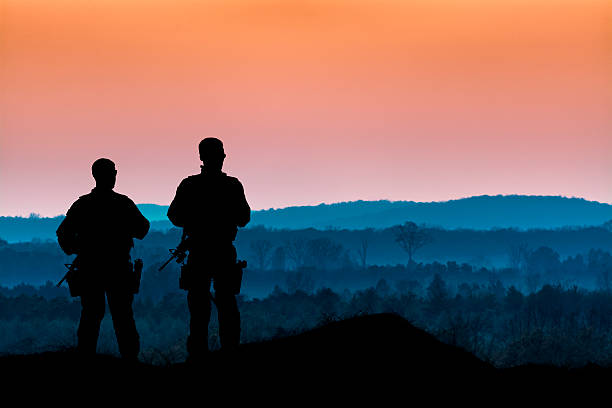 istock Men with Guns Overlook a Forest at Dusk 496825588