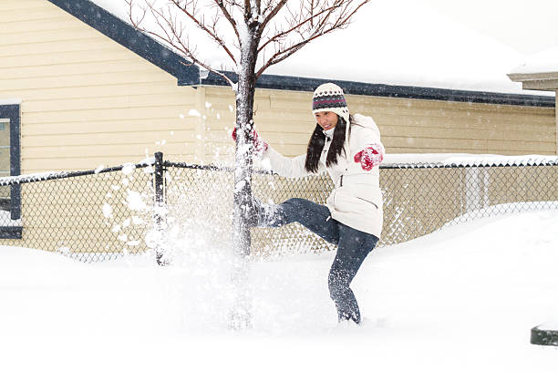 Young Chinese girl kicks snow while playing outside during Winter.