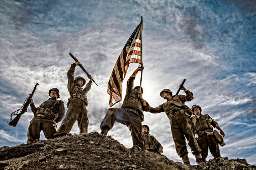 War World ll solders standing on a hill holding and carrying the American flag. Iwo Jima Concept photo.