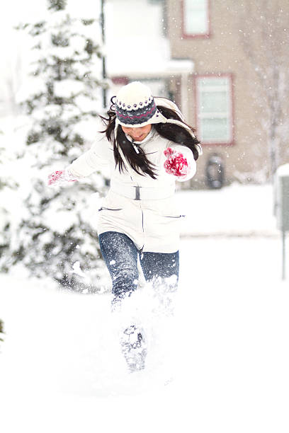 Young Chinese girl running through the snow, while playing outside during Winter.