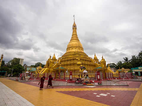 Mandalay, Myanmar - August 13, 2013: Young monks pass by one of Mandalay's many golden temples