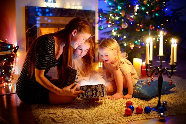 istock Mother and two little daughters opening a magical Christmas gift 496828548