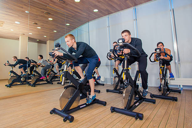 Group of gym people on machines, cycling In Class