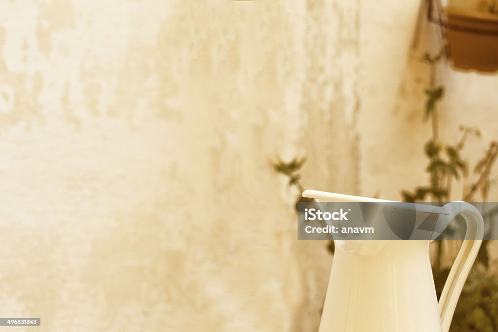 Jug with patio wall in the background White jar in a patio with vegatation.. White jar in a courtyard with greenery.. Brocca bianca in a cortile with vegatazione. Chopped Food Stock Photo