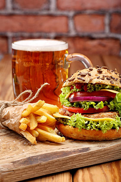 istock Grilled hamburger with fries and beer on brick wall background 496833152