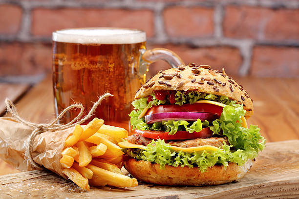 istock Grilled hamburger with fries and beer on brick wall background 496833178