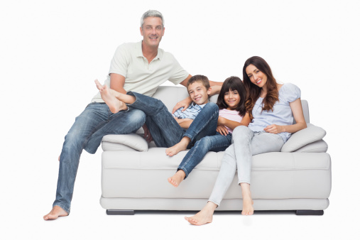 Family sitting on sofa smiling at camera on white background