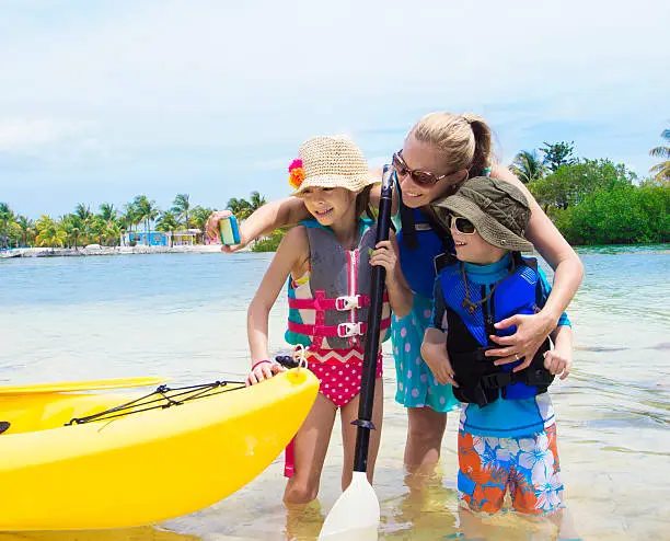 Photo of Woman with two children next to yellow kayak