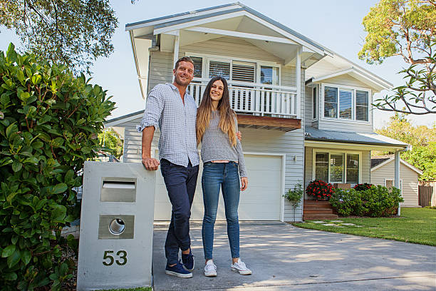 couple standing by their mailbox in front of new home stock photo