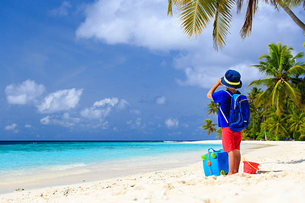 istock little boy travel on beach with suitcase and binoculars 496848566