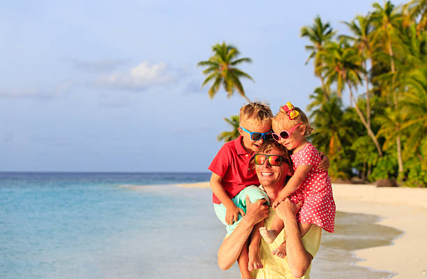 istock happy father with two kids on shoulders at beach 496848850