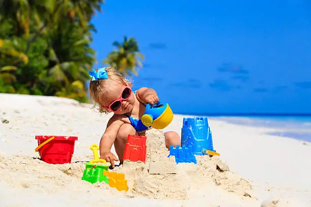 Photo of cute little girl playing with sand on beach