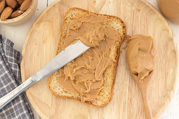 istock Peanut butter  with nuts on wooden table 496851688